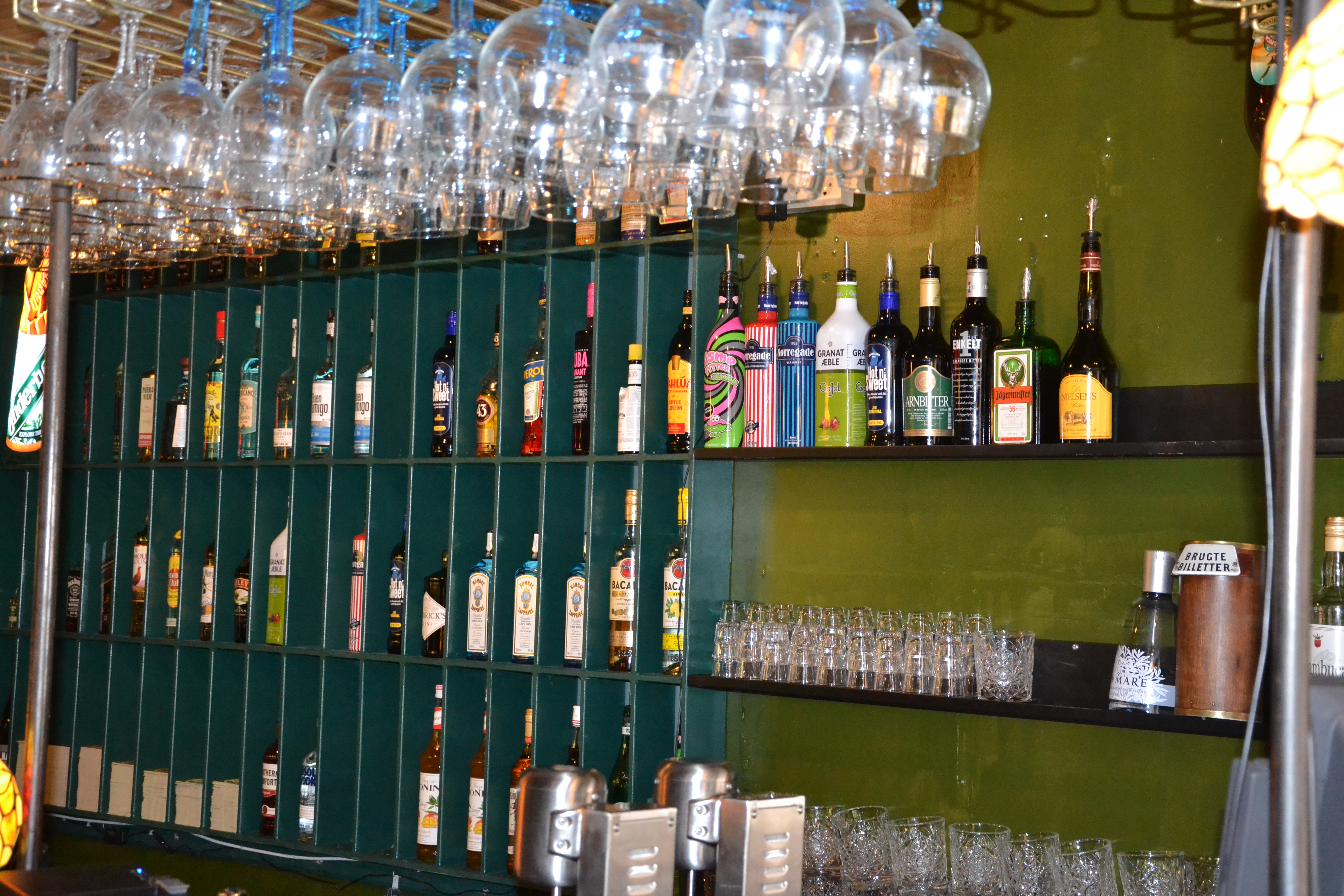 Imponerende bar-opstilling med hængende vinglas og omfattende spiritus-udvalg